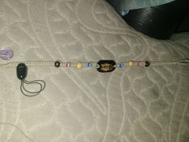 Flat-knotted hemp bracelet with coloured beads and a carved wooden fish bead in the centre