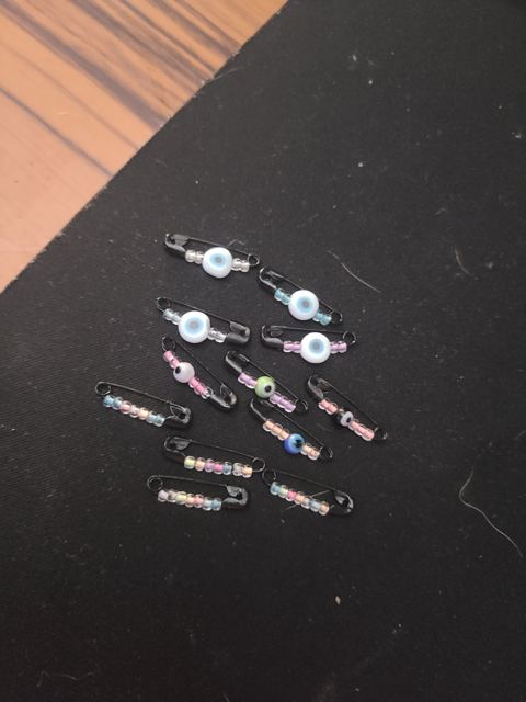 Black safety pins strung with pastel seed beads and evil eye beads