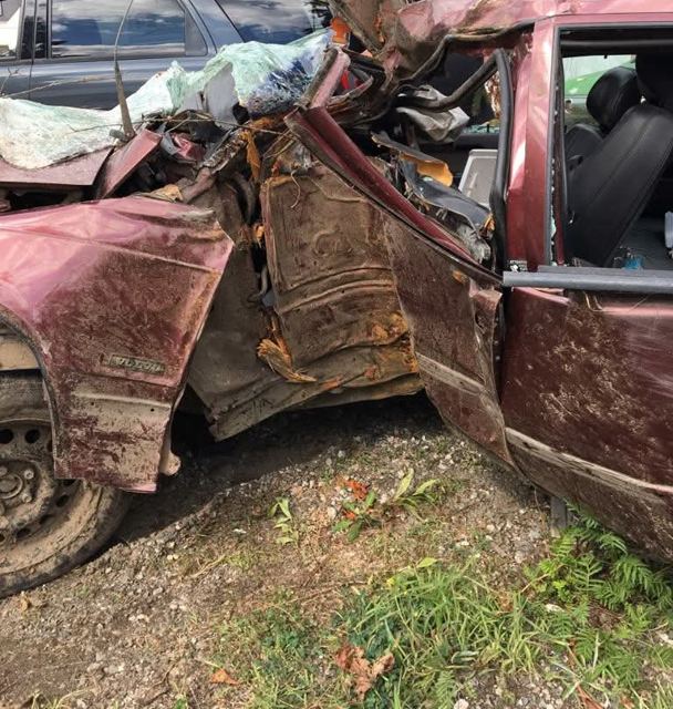 Crushed maroon car with the roof and driver side torn open
